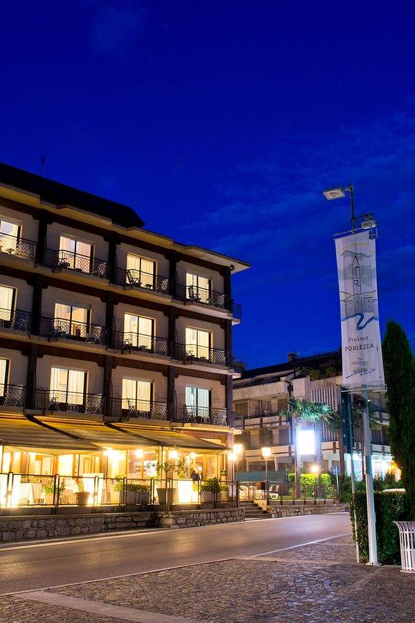 Hotel Europa Porlezza illuminated facade with palm trees on Lake Lugano